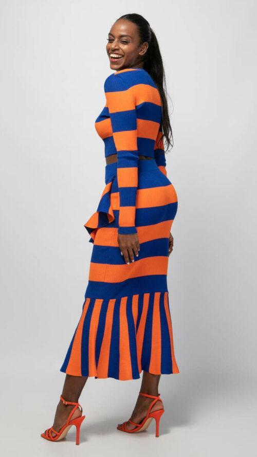 Midi ριγέ μπλε με πορτοκαλί φούστα με στενή εφαρμογή, ελαστική μέση και λεπτομέρειες με βολάν. Εμφάνιση στο πλάι