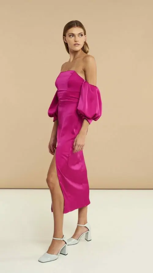 Μίντι σατέν φόρεμα με κοντά φουσκωτά μανίκια, άνοιγμα στο αριστερό πόδι και κρυφό φερμουάρ. Εμφάνιση στο πλάι